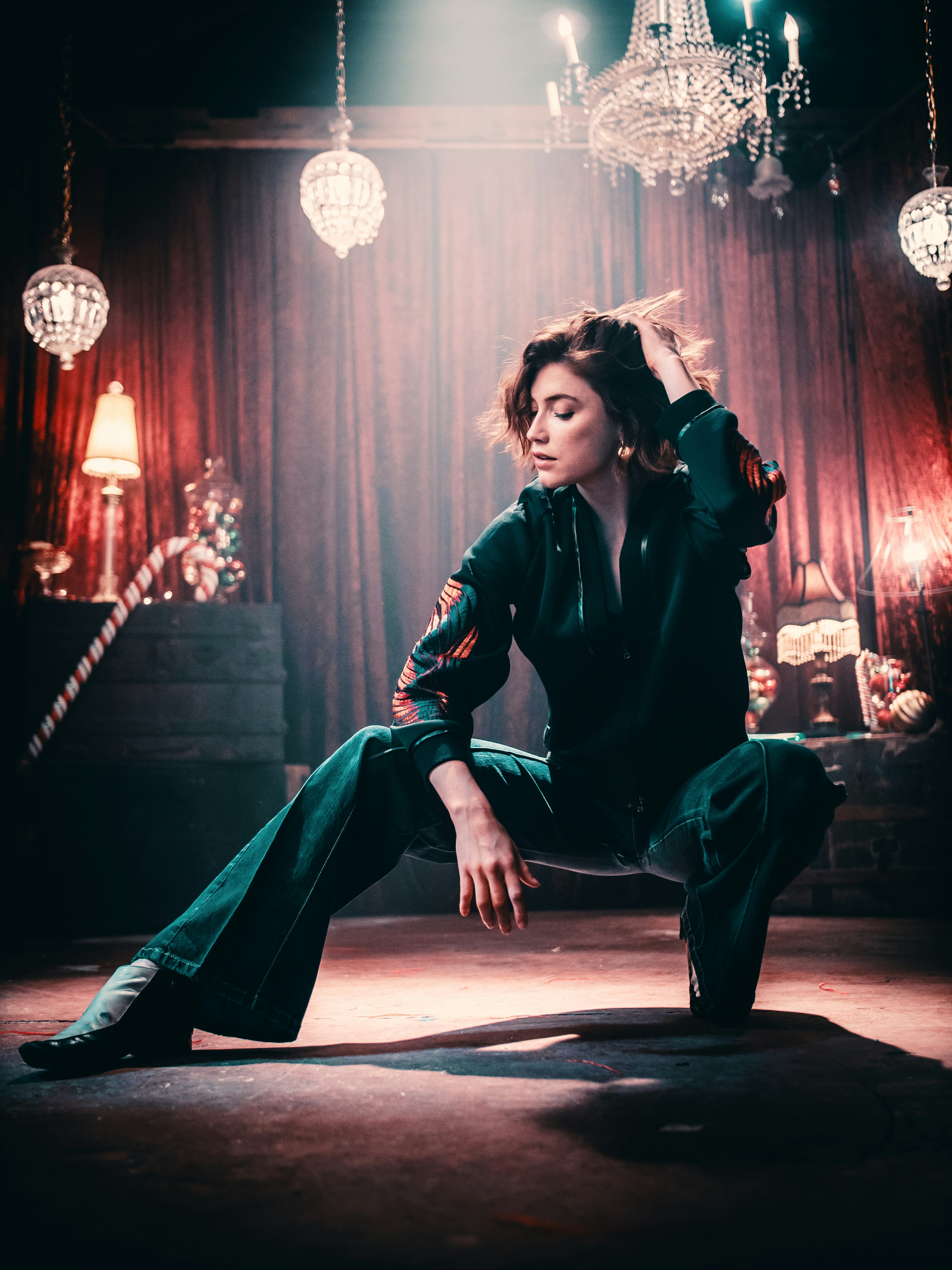 woman in green long-sleeved shirt posing under chandelier